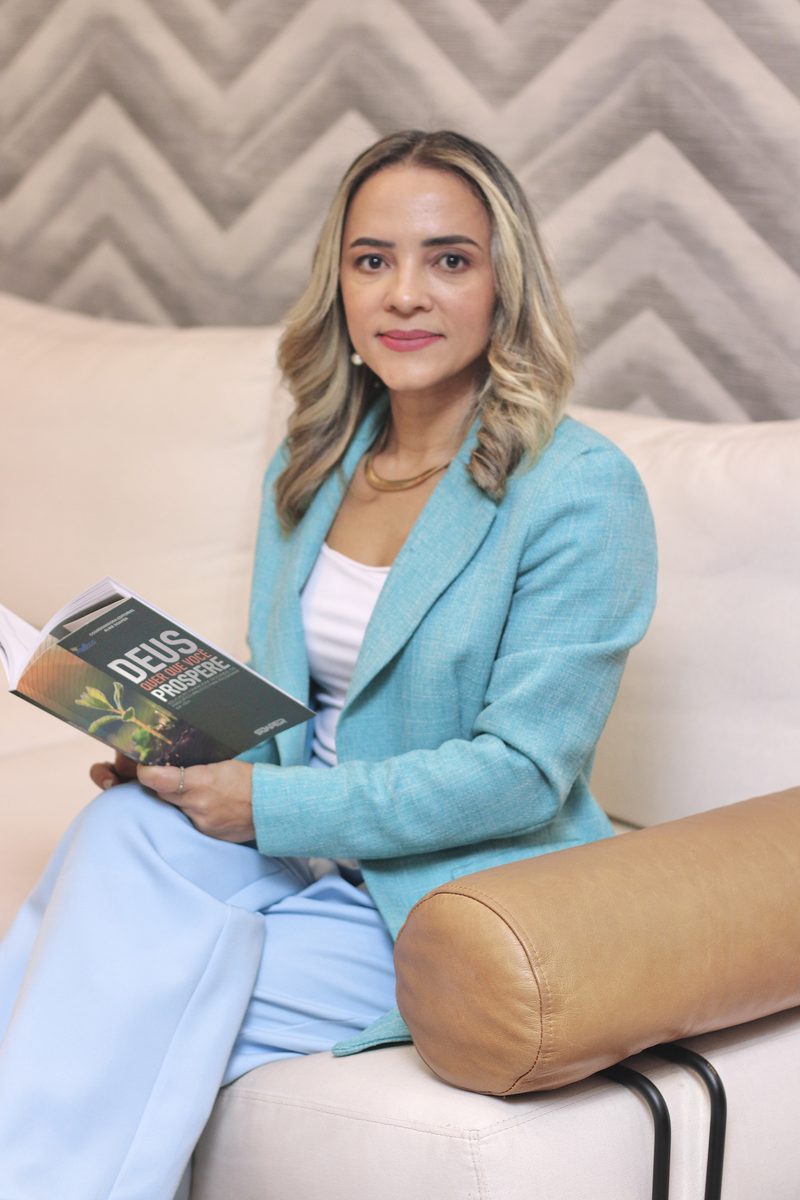 Aildes Souza, especialista em finanças, segurando um dos livros de que é coautora